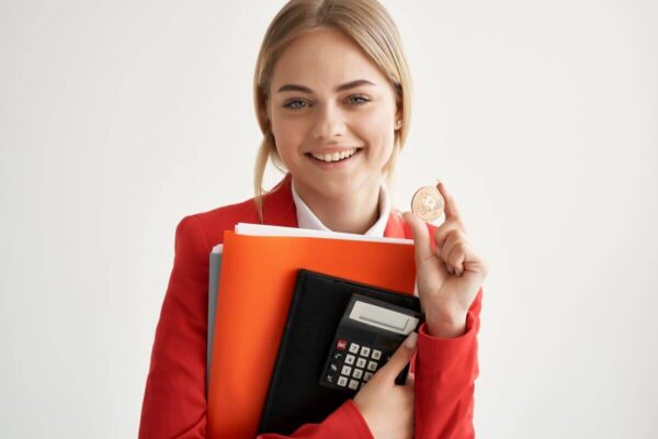 Młoda księgowa trzyma kalkulator i monetę.