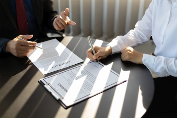 Osoby podpisują dokumenty związane z zakładaniem spółek.