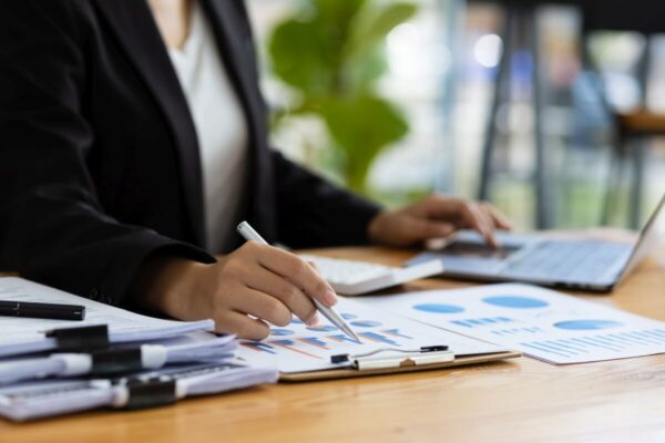 Księgowa analizuje dokumenty finansowe przy biurku z laptopem.