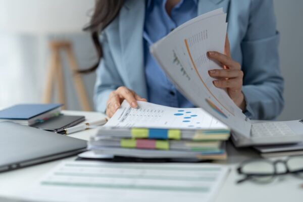 Księgowa przegląda dokumenty finansowe na biurku.