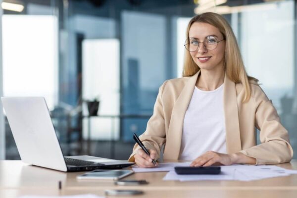 Księgowa pracuje przy biurku z laptopem i dokumentami.
