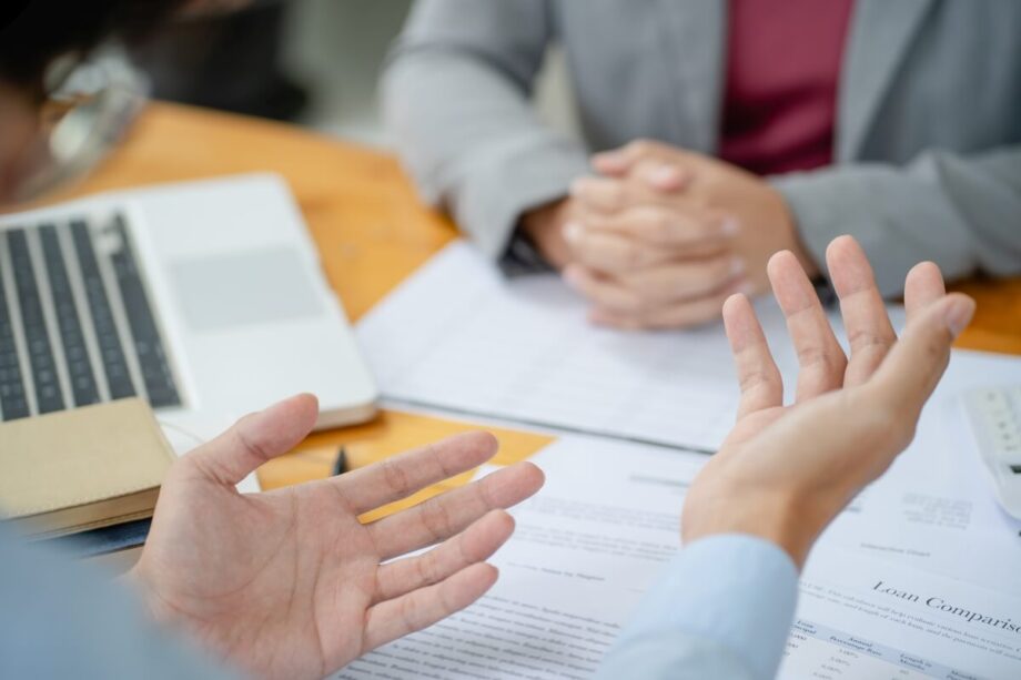 Dwie osoby przy biurku omawiają dokumenty w biurze rachunkowym.