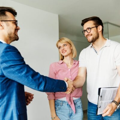 Trzech ludzi w biurze, uścisk dłoni symbolizuje pomoc w zakładaniu firmy.