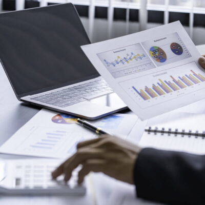 Osoba przegląda dokumenty finansowe przy laptopie, skupiając się na pełnej księgowości.