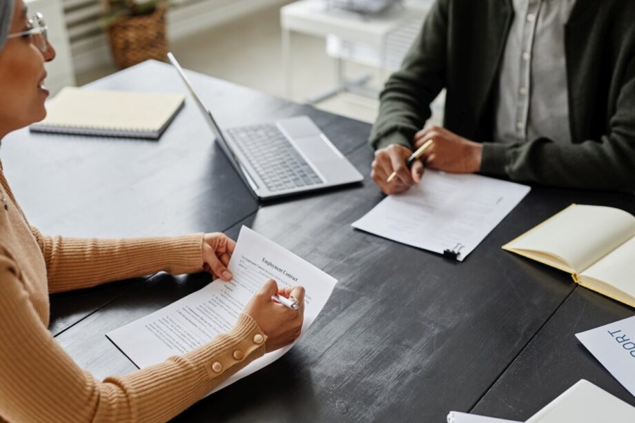 Dwie osoby siedzą przy stole z dokumentami, omawiając zakładanie spółek.
