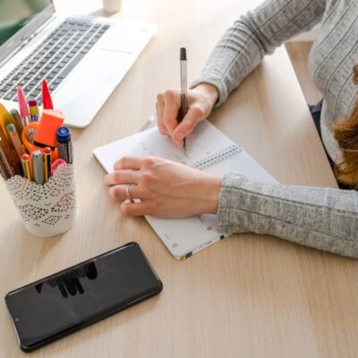 Osoba robi notatki przy biurku, korzystając z laptopa świadczącego usługi księgowe.