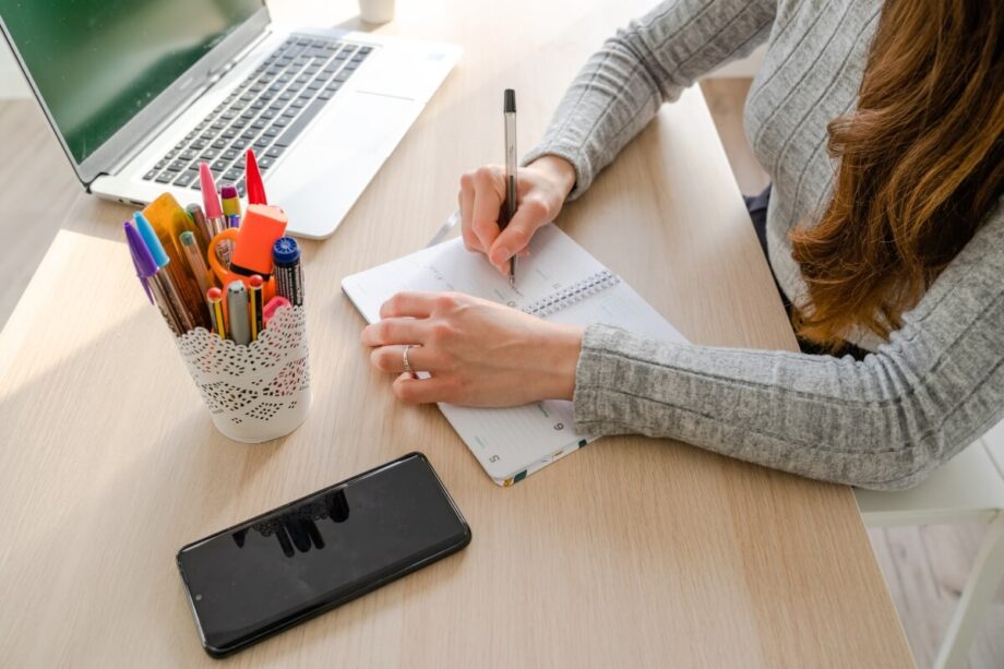 Osoba robi notatki przy biurku, korzystając z laptopa świadczącego usługi księgowe.