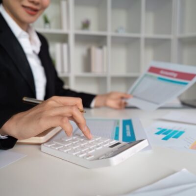 Osoba w garniturze wykonuje usługi księgowe przy użyciu kalkulatora.