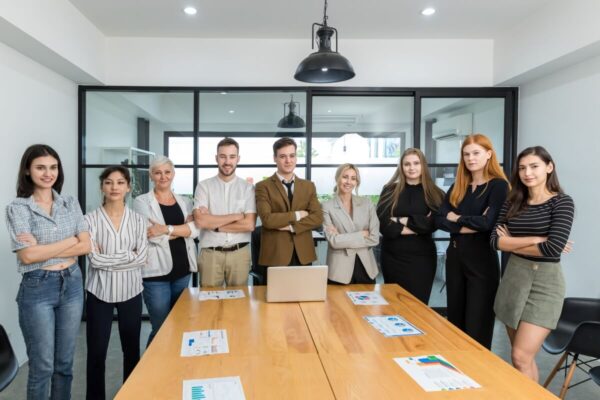 Grupa profesjonalistów oferujących pomoc w zakładaniu firmy stoi wokół stołu konferencyjnego.