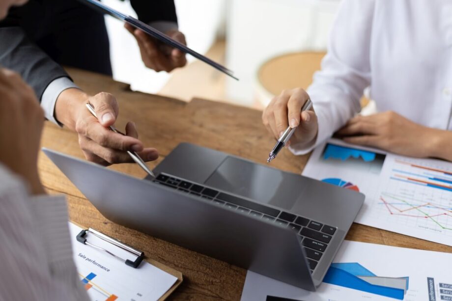 Osoby pracujące przy komputerze omawiają raporty w biurze rachunkowym.