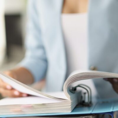 Osoba przegląda dokumenty, co symbolizuje pełna księgowość.