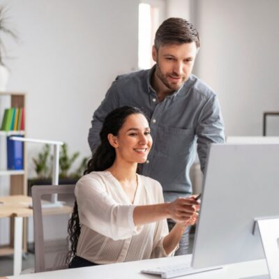 Księgowa pracuje przy komputerze, a kolega jej pomaga.