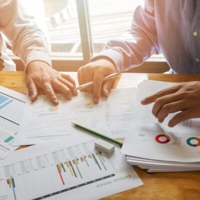 Dwóch mężczyzn analizuje dokumenty finansowe związane z pełną księgowością.