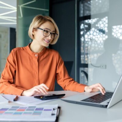 Księgowa pracuje przy biurku na laptopie.
